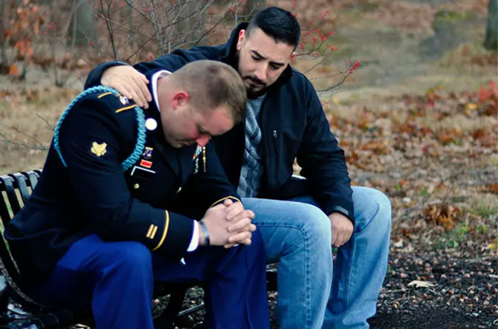 Friend consoling soldier on park bench